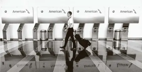  ?? Andrew Caballero-Reynolds / Getty Images ?? An airline employee walks past empty American Airlines check-in terminals at Ronald Reagan Washington National Airport in Arlington, Va. The industry is reining in spending and reducing flights amid a shaky demand environmen­t.