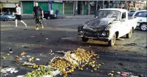  ?? AP/SANA ?? Two men walk past the site of a suicide attack Wednesday in Sweida, Syria. The bombing in southern Syria was part of a coordinate­d wave of violence by the Islamic State that left scores of people dead.