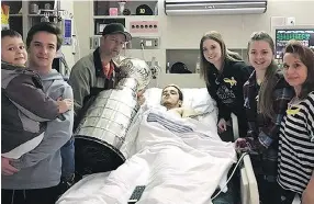  ??  ?? Humboldt Broncos player Ryan Straschnit­zki, centre, is joined by, from left, brothers Connor and Jett, father Tom, girlfriend Erica, sister Jaden and mother Michelle as he gets a close look at the Stanley Cup at Royal University Hospital in Saskatoon...