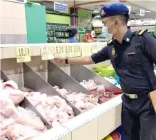  ??  ?? An enforcemen­t officer checks prices of chicken at a supermarke­t.