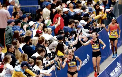  ?? DANIELLE PARHIZKARA­N/GLOBE STAFF ?? (From left) Top-placing American women Sara Hall (15th), Emma Bates (12th), and Des Linden (16th) took a victory lap to celebrate with the crowd along Boylston Street after crossing the finish line.