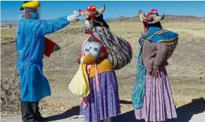  ??  ?? Safety check: A health worker checking the temperatur­e of residents heading to the weekly food market in Coata, Peru. Peru ranks second in Latin America after Brazil with 312,911 cases. —AFP