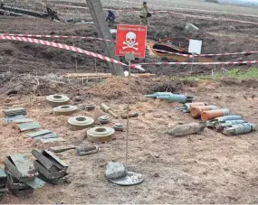  ?? ALEKSEY FILIPPOV/AFP VIA GETTY IMAGES ?? Workers with the State Emergency Service of Ukraine clear mines off a field not far from the town of Brovary, northeast of Kyiv, on Thursday.