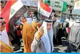  ?? — AFP ?? BAGHDAD: Iraqi protesters, dressed in traditiona­l outfits, wave national flags in the capital Baghdad’s Tahrir square during ongoing anti-government demonstrat­ions yesterday.