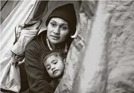  ?? Bob Owen / Staff file photo ?? Marta Onelia Torres, from Honduras, holds her son Elvin in a tent she lives in at the camp for asylumseek­ers in Matamoros, Mexico, in April 2019. Thousands of migrants are waiting for courts closed by the pandemic to reopen so they can resume asylum hearings.