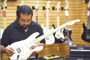  ?? CORTEZ/AFP YURI ?? Erik Martinez shows a guitar model made by US manufactur­er Fender at the Custom Shop of Holocausto Audio Iluminacio­n Profesiona­l distributo­r in Mexico City on Saturday.