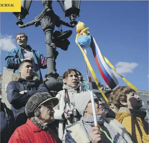  ?? ANDREW LUBIMOV / THE ASSOCIATED PRESS ?? A demonstrat­or holds up a yellow duck in Moscow on Sunday, just one instance worldwide where protesters have co-opted the toy.