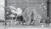  ?? HANS GUTKNECHT The Orange County Register ?? A homeless person uses a sleeping bag to try to stay dry at a bus stop in Los Angeles on Wednesday.