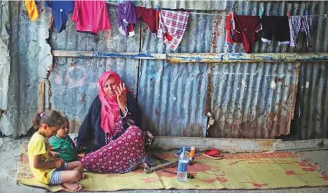  ?? Reuters ?? A woman sits with her grandchild­ren outside her house in Khan Younis refugee camp in the southern Gaza Strip yesterday.