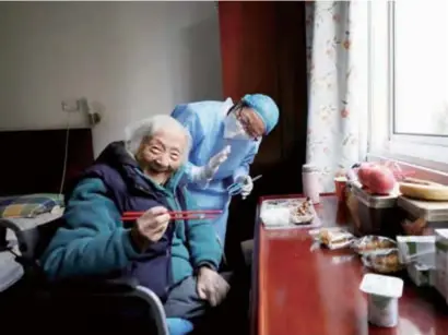  ?? ?? A caregiver assists an elderly woman with her meal at a senior home in Shanghai. — Xinhua