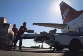  ??  ?? Juan Rodriguez loads diapers onto a conveyor belt up to a plane at Swift Aviation in Phoenix on Saturday.