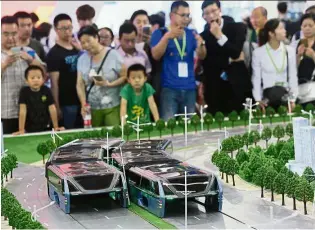  ?? — AP ?? er ead transit People looking at a model of an electric ‘lanestradd­ling bus’ at the 19th China Beijing Internatio­nal High-tech Expo.