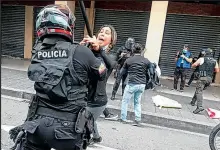  ??  ?? Una mujer es intercepta­da por un policía, quien levanta el tolete para amenazarla.