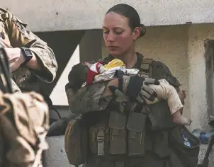  ?? Sgt. Isaiah Campbell, U.S. Marine Corps via The Associated Press ?? U.S. Marine Sgt. Nicole Gee calms an infant during an Aug. 20 evacuation at the airport in Kabul, Afghanista­n. Gee was one of the Marines killed in the Aug. 26 bombing at the airport.