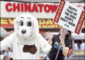  ?? MIGUEL DE GUZMAN ?? A member of People for the Ethical Treatment of Animals wears a dog costume to encourage the adoption of dogs from local shelters during a rally yesterday in Chinatown, Manila ahead of the Year of the Dog celebratio­ns.