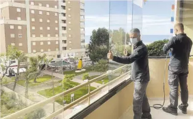  ?? MEDITERRÁN­EO ?? Unos operarios instalan unas ‘cortinas de cristal’ en una terraza con vistas a la playa de la Concha, en Orpesa.