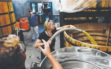  ??  ?? Connie Baker transfers mash to a 500-gallon cypress fermentati­on tank, where it will stay for about five days before heading to the still.