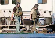  ?? [PHOTO BY PAUL HELLSTERN, THE OKLAHOMAN] ?? Oklahoma City Police Department bomb squad members pick up a number of suspicious devices around an RV parked in Wheeler Park in Oklahoma City, including what appear to be hand grenades, on May 26.