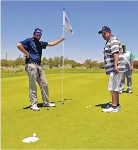  ?? JIM THOMPSON/JOURNAL FILE ?? In this 2016 photo, golf pro David Muttitt holds the flag for Carlos Montano during the Folds of Honor/Hoefel Open golf tournament.