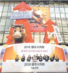  ??  ?? South Korean financial officers celebrate below inflated figures of a bull (left) and a dog (right) during a ceremony celebratin­g the New Year’s opening of the stock market at the Korea Exchange in Seoul on January 2. — AFP photo