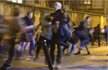  ?? PETER DEJONG/THE ASSOCIATED PRESS ?? A man carries two children after panic broke out Sunday in Paris among mourners at two of the sites attacked.