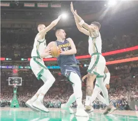  ?? WINSLOW TOWNSON/AGENCE FRANCE-PRESSE ?? DENVER’S Nikola Jokic gets double-teamed by the Boston duo of Kristaps Porzingis and Jayson Tatum but the Nuggets still edge the Celtics, 102-100, in their NBA regular season game.