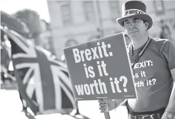  ??  ?? Anti-Brexit campaigner Steve Bray stands outside parliament with EU and Union Flags and a placard that reads ‘Brexit: is it worth it?’ as he protests in Parliament Square in London. — AFP photo