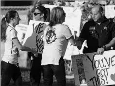  ?? ASSOCIATED PRESS ?? FACULTY AND STAFF GREET POLICE OFFICERS STATIONED OUTSIDE Stoneman Douglas High School on Wednesday in Parkland, Fla. of Marjory