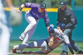  ?? THE ASSOCIATED PRESS ?? Colorado Rockies second baseman D.J. LeMahieu, left, applies a late tag as Atlanta’s Freddie Freeman slides safely into second base with a double in the first inning of Sunday’s game in Denver. Second base umpire Nic Lentz, right, watches the play. The...