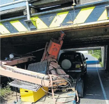  ??  ?? No through road...a trailer carrying machinery, left, and a van are stuck fast under the 7ft bridge in Stonea, Cambs. Below, the height restrictio­n can be seen clearly, except, it seems, by drivers