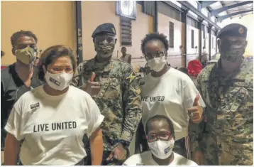  ??  ?? United Way of Jamaica Team of volunteers take a break from packing care packages to pose with JDF Officers