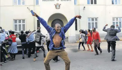  ?? EFE / KIM LUDBROOK ?? Varias personas celebran la renuncia de Mugabe ante el Parlamento de Zimbabue, ayer en Harare.