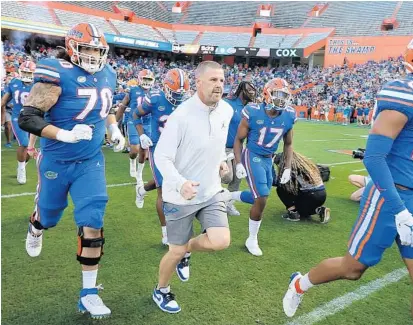  ?? STEPHEN M. DOWELL/ ORLANDO SENTINEL ?? UF coach Billy Napier (middle) and players run onto the field during the Orange & Blue Game last month. Napier developed a reputation while at Louisiana for his analytical approach. He brought those methods with him to Florida.
