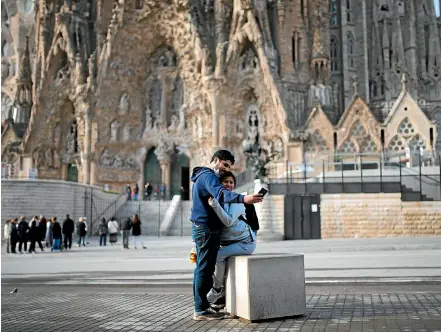  ??  ?? A couple take a selfie outside the normally bustling Sagrada Familia basilica in Barcelona yesterday. Spain has declared a state of emergency as Europe tries to contain the spread of the Covid-19 coronaviru­s.
