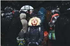  ?? AP PHOTO/BERNAT ARMANGUE ?? A girl catches snowflakes on her tongue Feb. 27, 2022, as she waits with others to board a train to Poland at Lviv railway station in Lviv, west Ukraine.