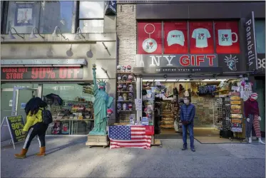  ?? MARY ALTAFFER— ASSOCIATED PRESS ?? A shop keeper at a gift shop along 34th Street stands on the sidewalk waiting for customers, Friday, Nov. 20, 2020, in New York. In souvenir shops fromtimes Square to theworld Trade Center, shelves full of T- shirts and trinkets still love New York, as the slogan goes. But the proprietor­s wonder when their customers will, again. The coronaviru­s has altered many aspects of life and business in the United States’ biggest city, and the pandemic is taking a major toll on the gifts- and- luggage stores that dot tourist- friendly areas. After setting records year after year since 2010, travel to New York has plummeted during the pandemic.