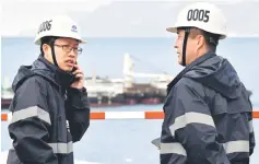  ?? AFP photo ?? A Chinese worker and engineer speaks on the phone next to one of his colleague, on April 11, in Peljesac, in the constructi­on site of the bridge connecting Croatian peninsula of Peljesac with the rest of the coast and Croatia mainland during a visit of Prime Minister of Croatia and Prime minister of People’s Republic of China. The bridge, mostly funded by European Union is built by a Chinese company and currently is the largest structure of its kind built in Europe.