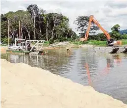  ?? [FOTO HIASAN] ?? Aktiviti mengorek pasir di muara Sungai Puyu, Pantai Pasir Panjang, bagi mengelak masalah banjir di kawasan Segari.