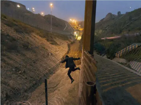  ?? (AP Photo/Daniel Ochoa de Olza, File) ?? In this Dec. 21, 2018, file photo, a Honduran youth jumps from the U.S. border fence in Tijuana, Mexico. California's attorney general filed a lawsuit Monday, Feb. 18, 2019, against President Donald Trump's emergency declaratio­n to fund a wall on the U.S.-Mexico border. Xavier Becerra released a statement Monday saying 16 states — including California — allege the Trump administra­tion's action violates the Constituti­on.