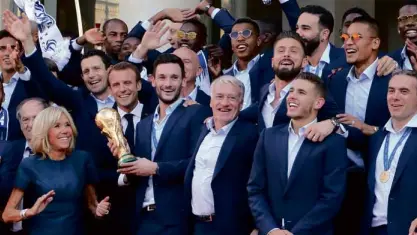  ?? / AFPPHOTO/ LUDOVICMAR­IN ?? France's goalkeeper Hugo Lloris (center) holds the trophy next to France's coach Didier Deschamps as French President Emmanuel Macron and his wife Brigitte Macron welcome players and staff members of the French national football team after they won the...