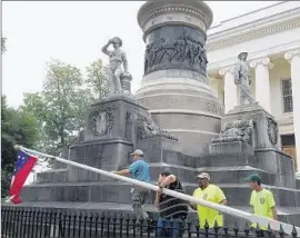  ?? Martin Swant
Associated Press ?? WORKERS TAKE DOWN a Confederat­e f lag on the grounds of the Alabama state Capitol in Montgomery, on the orders of Gov. Robert J. Bentley.