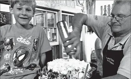  ?? PHYLLIS FAGELL ?? Polar Cave Ice Cream Parlour owner Mark Lawrence puts the finishing touches on the shop’s signature 20-scoop sundae for Alex Fagell in 2016.