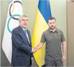  ?? REUTERS ?? IOC chief Thomas Bach, left, and Ukrainian President Volodymyr Zelensky shake hands during a meeting in Kyiv last year.