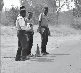  ??  ?? Police officers man a roadblock with metal spikes at hand along Nketa Drive in Kelvin Industrial Area, Bulawayo yesterday. The Government has stopped police from using metal spikes as new innovation­s to manage traffic are being introduced. (Picture by...