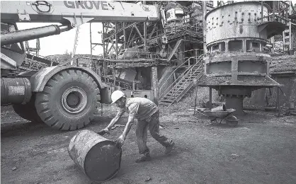  ?? AP ?? In this November 2, 2017 photo, a Ferrominer­a Orinoco worker rolls a en empty barrel in Ciudad Piar, Bolivar state, Venezuela. Venezuela sits atop the world’s largest oil reserves, but low crude prices and a plunge in production has left it in an...