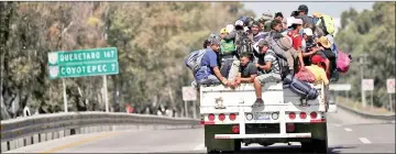  ??  ?? Migrants, part of a caravan of thousands traveling from Central America en route to the United States, hitchhike a ride along the highway as they make their way to Queretaro from Mexico City, Mexico. — Reuters photo