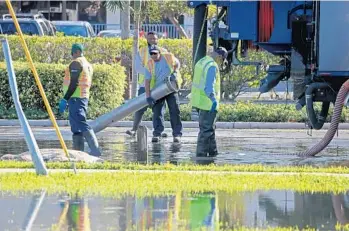  ?? SUSAN STOCKER/SUN SENTINEL PHOTOS ?? Workers vacuum waste water spilling onto Bayview Drive after a sewer main break Thursday at George English Park.