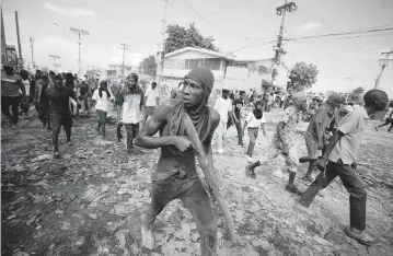  ?? ODELYN JOSEPH AP ?? A protester carries a piece of wood simulating a weapon during a protest demanding the resignatio­n of Prime Minister Ariel Henry, in the Petion-Ville area of Port-au-Prince, Haiti, on Oct. 3.