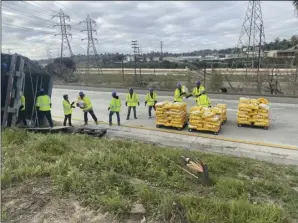 ?? Photo courtesy of California Highway Patrol ?? Caltrans workers offload a semi truck filled with pallets of dog food that overturned on Monday, causing the southbound Interstate 5 to be backed up for drivers’ morning commutes.