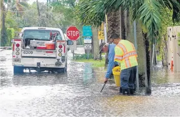  ?? JOE CAVARETTA/SUN SENTINEL PHOTOS ?? A Fort Lauderdale public works crew clears storm drains as floodwater­s rise in 2017. The National Oceanic and Atmospheri­c Administra­tion predicts an increase in the frequency of fair-weather flooding in the U.S. Southeast.